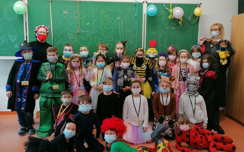 Verkleidete Kinder feiern Fasching im Klassenzimmer.