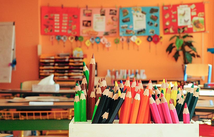 Blick in einer farbenfrohes Klassenzimmer, im Vordergrund sind bunte Stifte zu sehen.