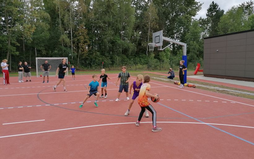 Kinder und Frauen spielen gemeinsam Basketball.