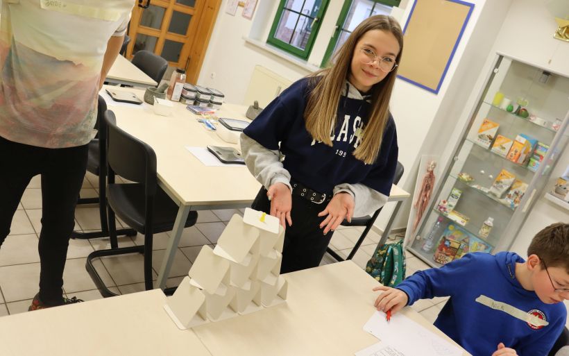 Eine Schülerin präsentiert die, gemeinsam mit Ihren Mitschülern gebauten, Kartenhäuser