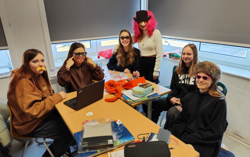 Mädchengruppe mit lustigen Masken, Brillen und Perücken.