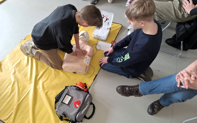 zwei Jungen üben die Arbeit mit einem Defibrillator